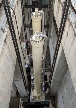 Two long stroke hydraulic cylinders for a large outlet gate being lowered by hoist upon installation at a hydroelectric dam .