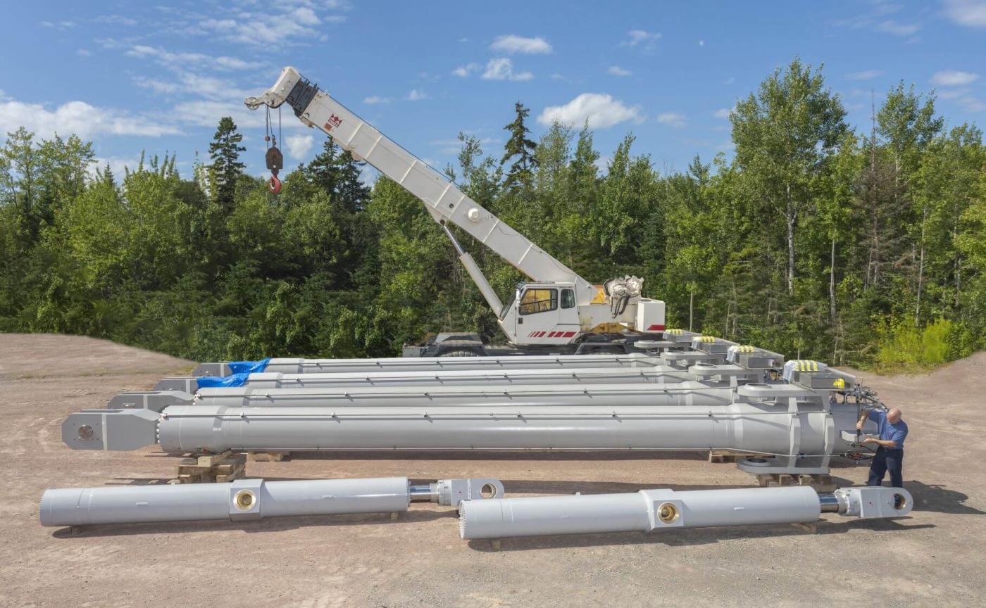 Large custom hydraulic cylinders for marine hydraulics project in front of crane prior to loading.