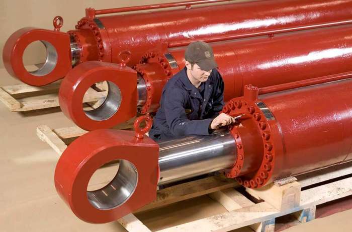 Technician inspecting large bore moonpool hydraulic cylinders after final assembly
