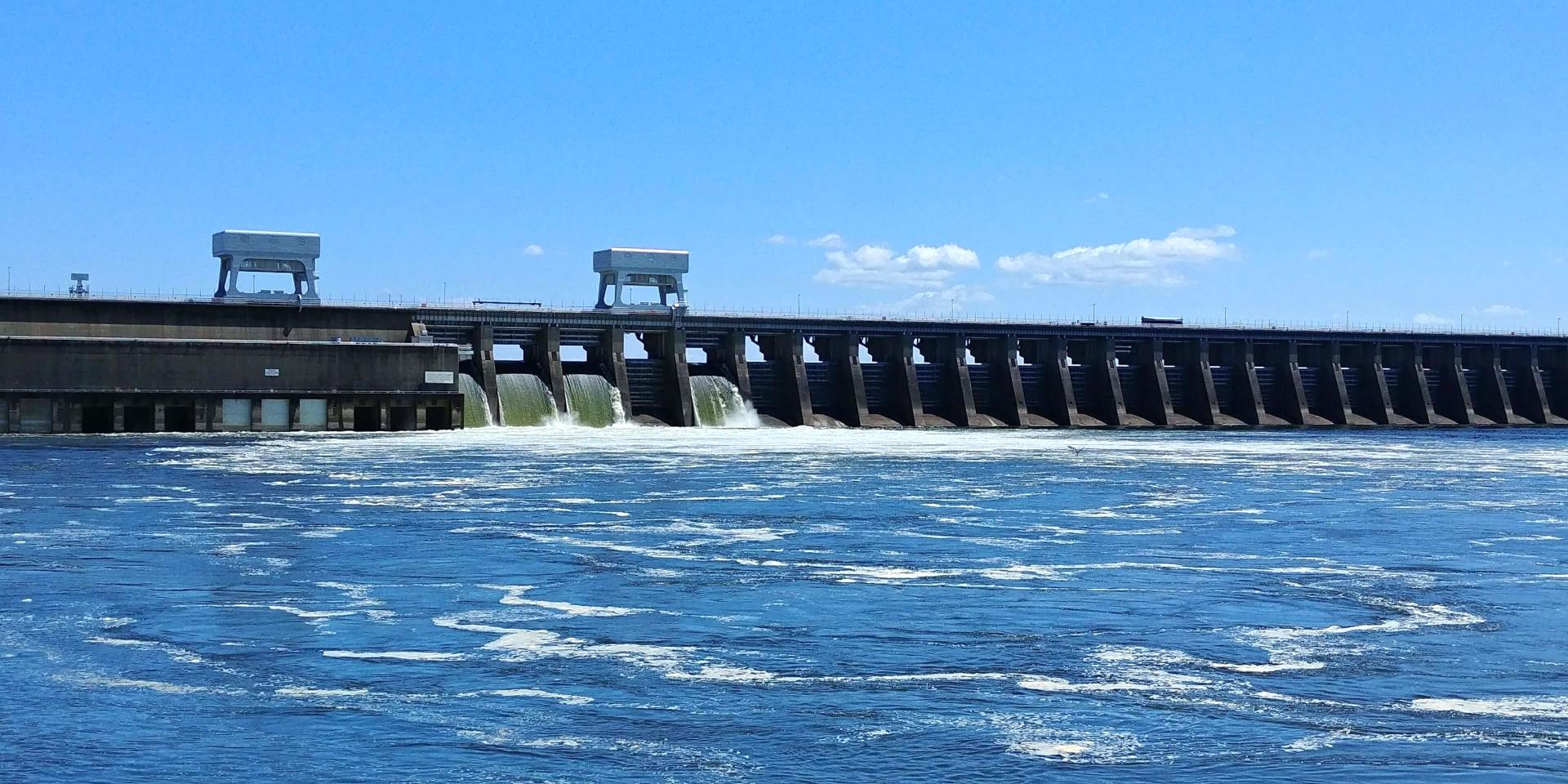 Dam with multiple radial gates and two railed gate hoists on sunny day