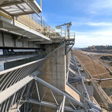 Perspective view from downstream side of eight main dam spillway gates on bright day 