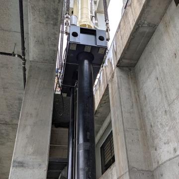 Long stroke hydroelectric dam gate cylinders on support beam being lowered into position upon installation